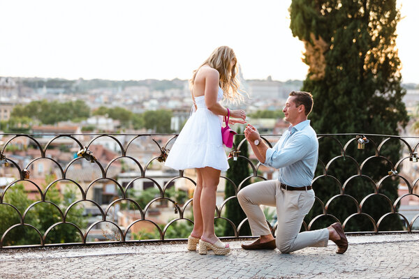 Beautiful couple during their Surprise marriage proposal at sunset on the Terrazza Belvedere in Rome