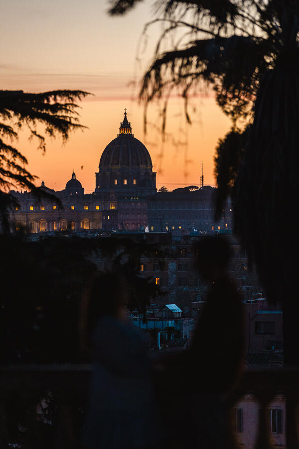 Silhouette of a newly-engaged couple with the Vatican in the background at sunset