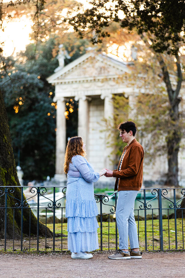 Couple holding hands by the pond in Villa Borghese during their surprise proposal shoot in Rome