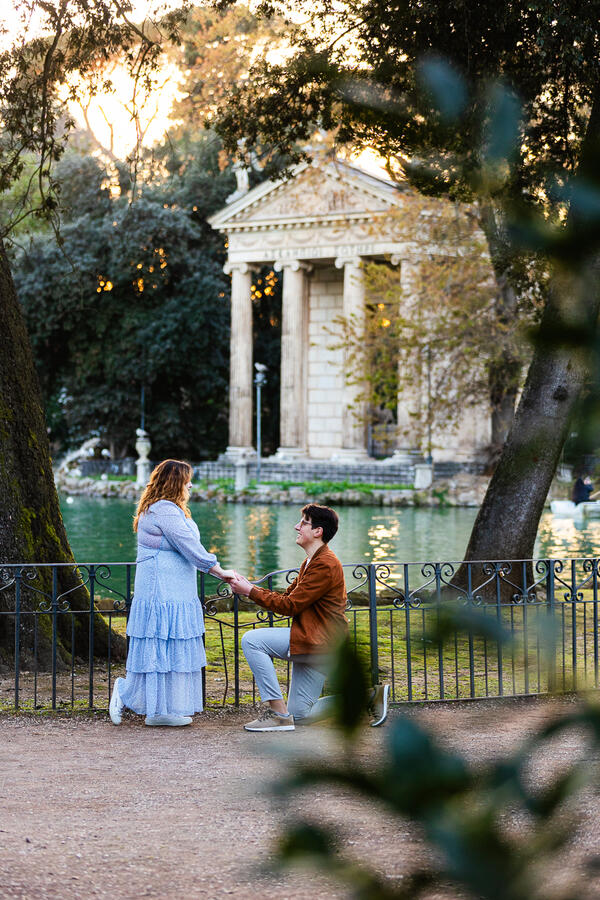 Surprise wedding proposal in Villa Borghese by the pond with the Asclepius Temple in the background in Rome