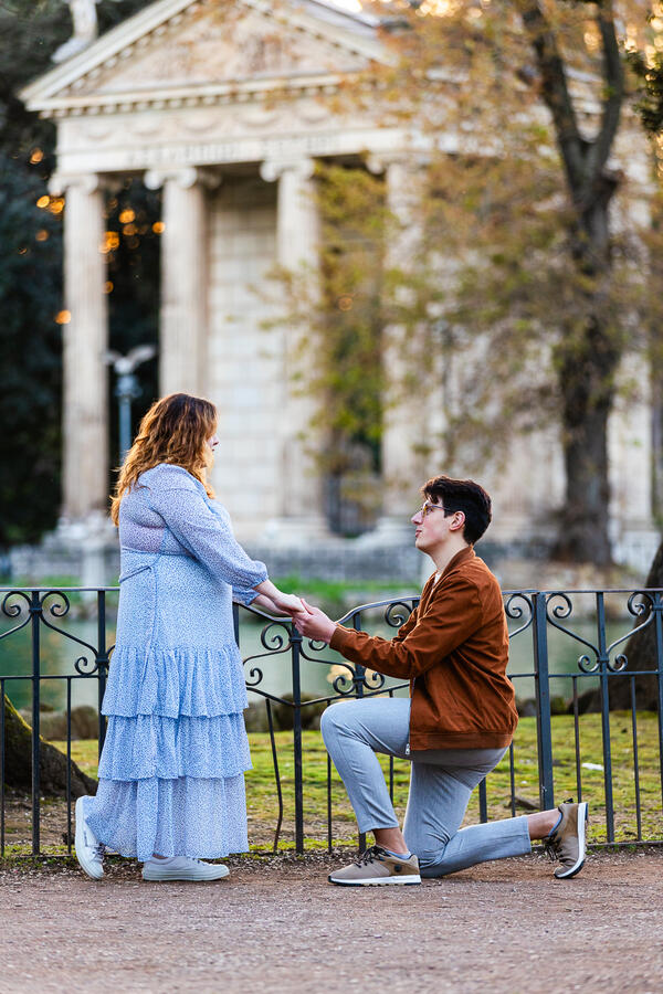 Close-up shot of a guy proposing in Villa Borghese by the pond in Rome