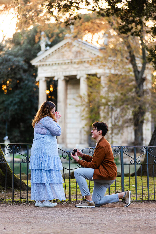 Guy with an engagment ring proposing in Villa Borghese by the pond in Rome