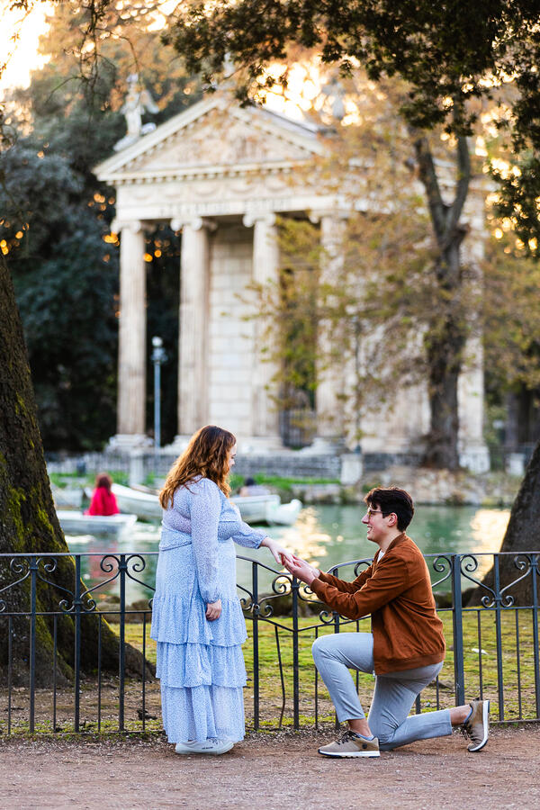 Surprise marriage proposal in Villa Borghese in Rome. Guy putting on the engagement ring while on his knee.