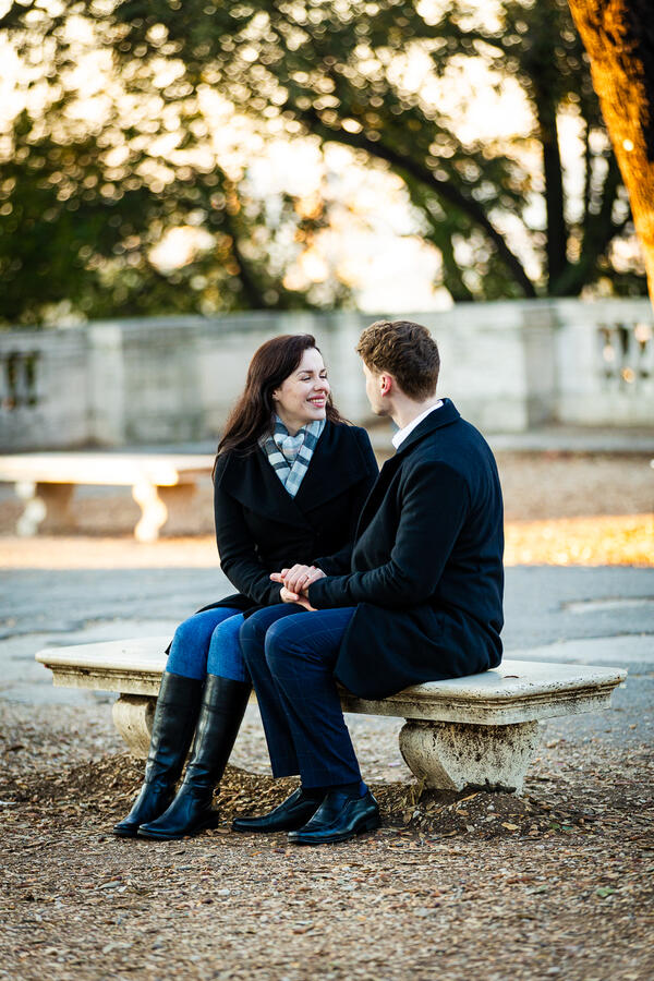 Happy newly-engaged couple sitting on a bench in the Pincio Gardens in Rome