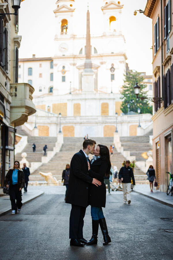 Beautiful newly-engaged couple kissing with the Spanish Steps in the background