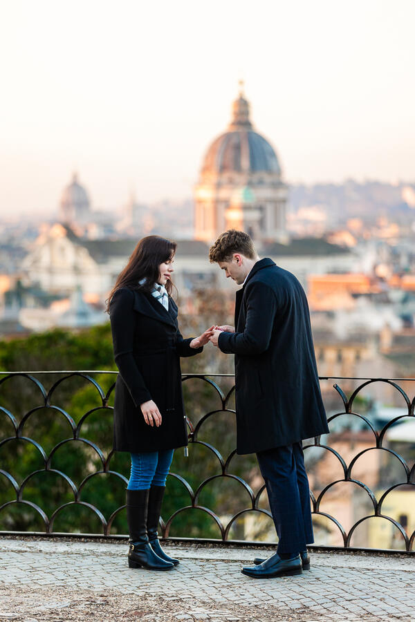 Young man putting the engagement ring on during his surprise proposal in Rome