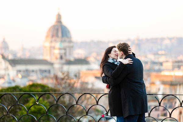 Newly-engaged couple kissing on the Terrazza Belvedere at sunrise