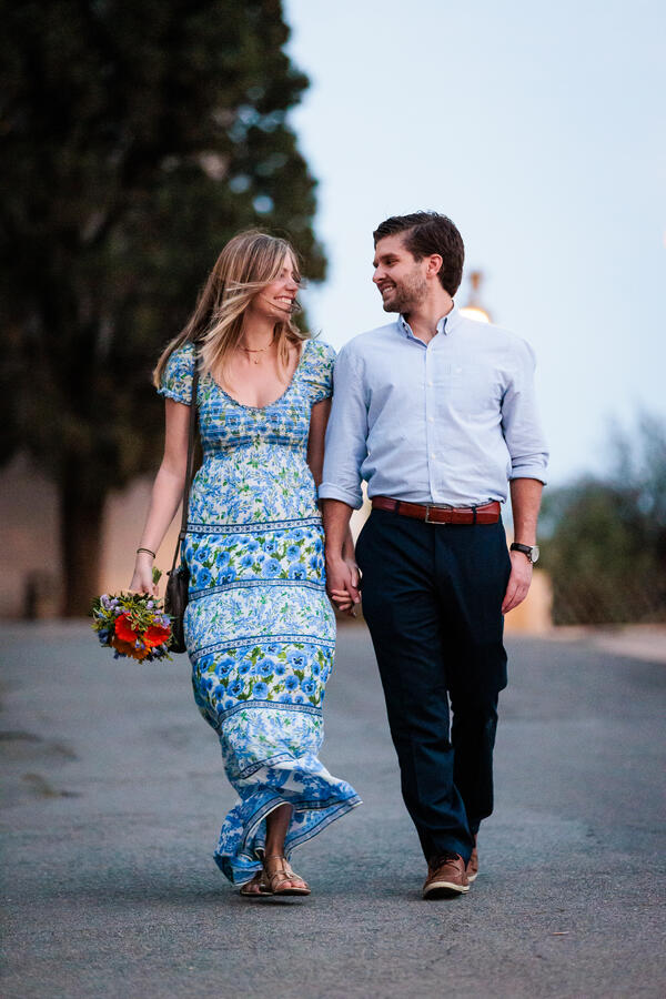 Happy couple on the Pincian Hill walking while smiling at each other during their wedding proposal photo session in Rome